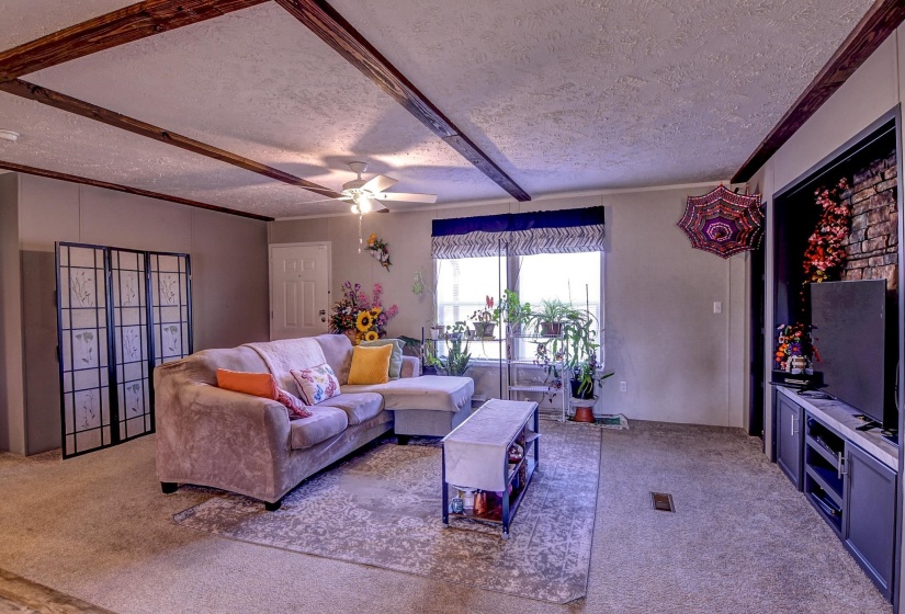 Carpeted living area with a textured ceiling and ceiling fan