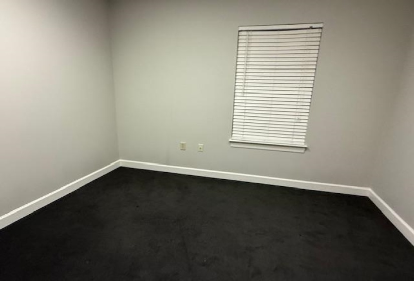 Spare room with dark carpet and baseboards