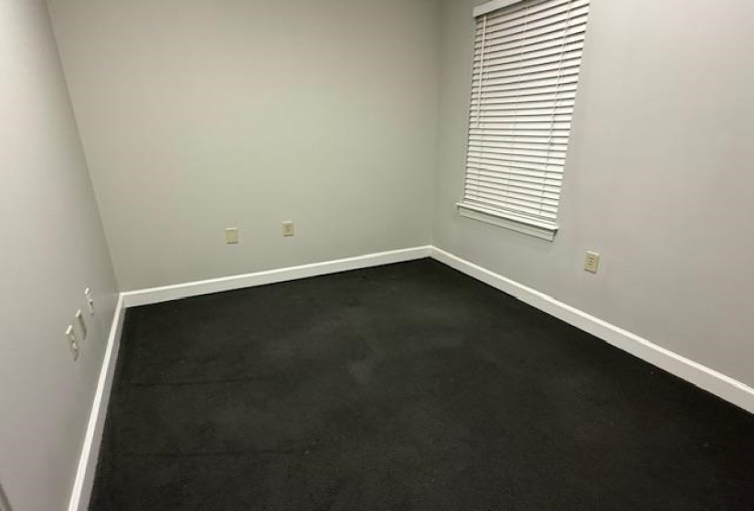 Empty room featuring dark carpet and baseboards