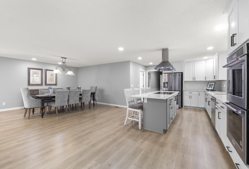 Dual tone kitchen featuring stainless steel appliances, a kitchen island, light stone counters, two tone cabinets, and island exhaust hood