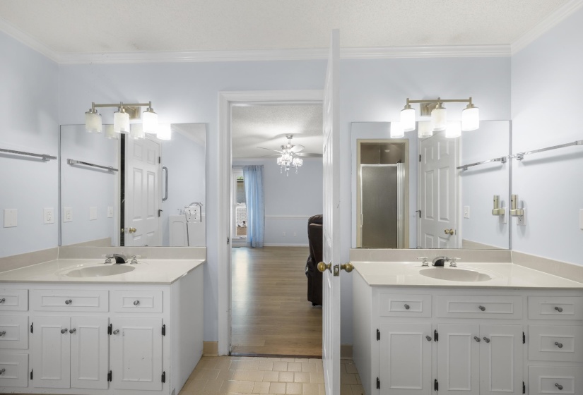 Bathroom with two vanities, ceiling fan, crown molding, a stall shower, and light tile patterned flooring