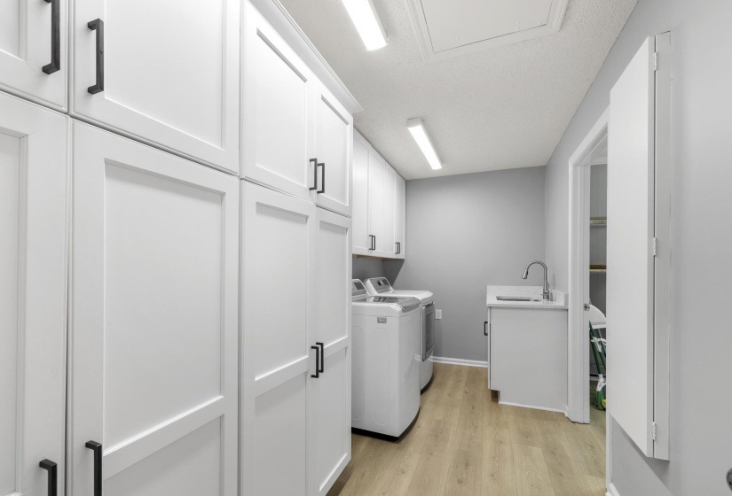 Laundry area with separate washer and dryer, light wood-type flooring, and cabinet space
