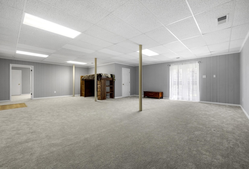 Play Room area with carpet floors, wood walls, and a paneled ceiling