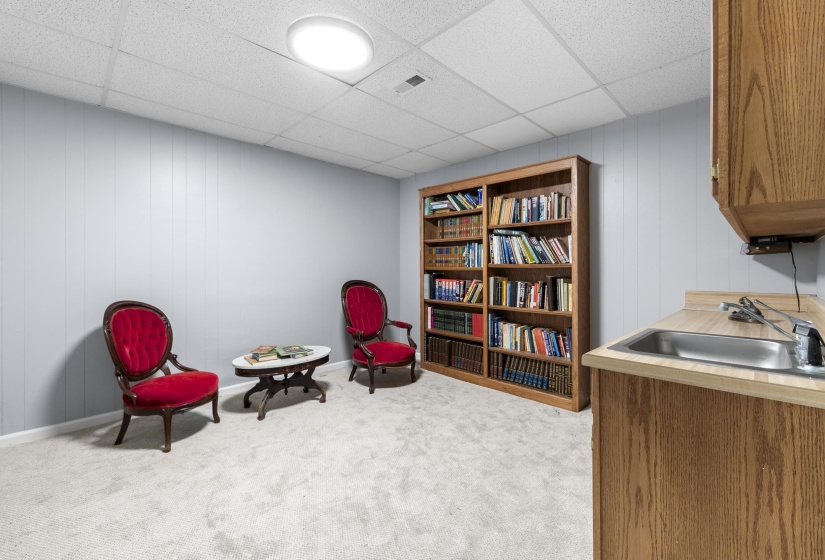 room with wooden walls, a drop ceiling, and light carpet