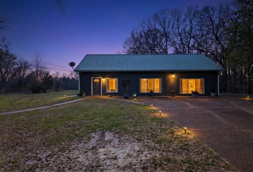 View of front of home featuring a metal roof, a lawn, covered porch, and concrete driveway