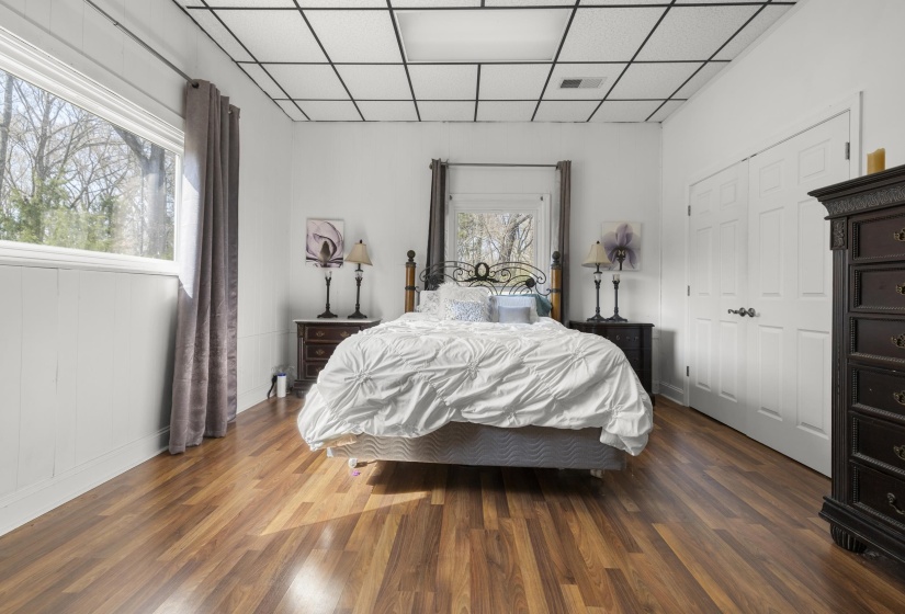 Bedroom with a drop ceiling, dark wood-style floors, and a closet