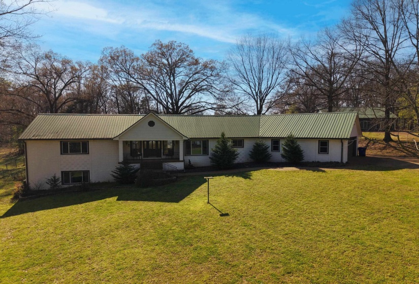 Ranch-style home with a porch, stucco siding, a front yard, and a metal roof