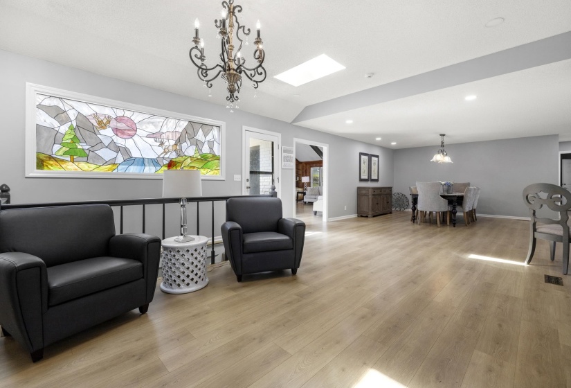 Living area featuring suspended lighting, light wood finished floors, and vaulted ceiling