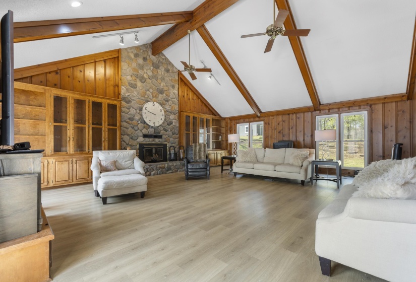 Family room featuring wood walls, wood finished floors, a stone fireplace, and track lighting