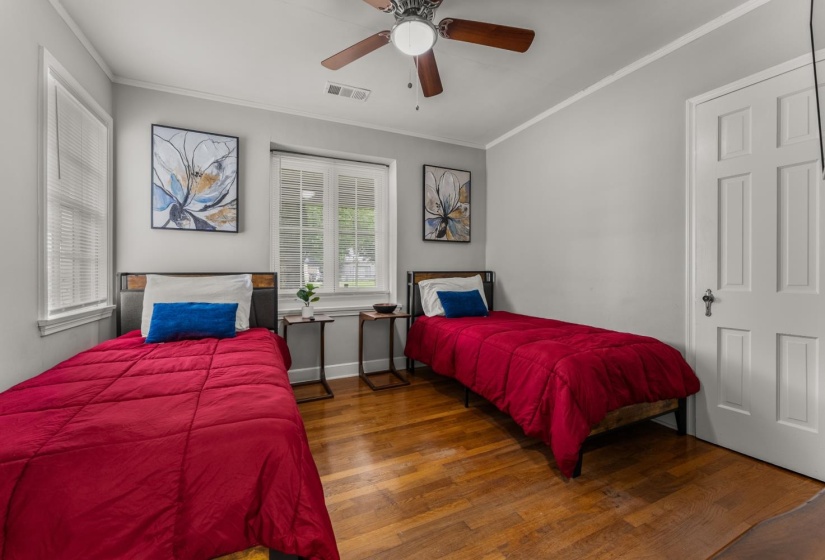 Bedroom with ornamental molding, wood finished floors, and a ceiling fan