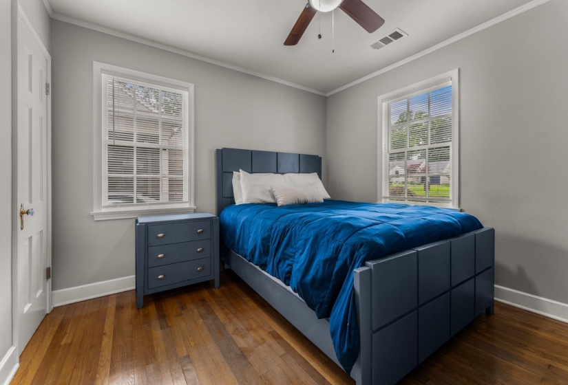 Bedroom featuring dark wood-style flooring, ornamental molding, and ceiling fan