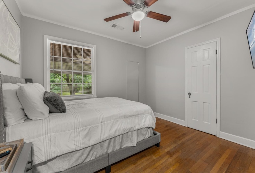 Bedroom with dark wood-style floors, crown molding, and a ceiling fan