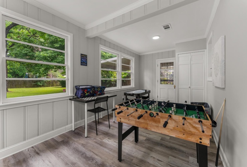 Recreation room featuring light wood-style flooring, ornamental molding, and a decorative wall