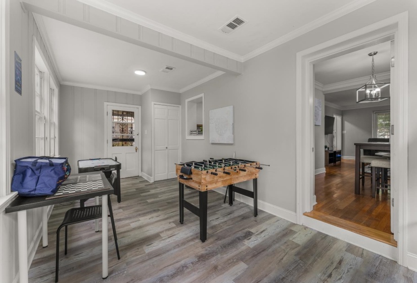 Rec room featuring light wood-type flooring, crown molding, and suspended lighting