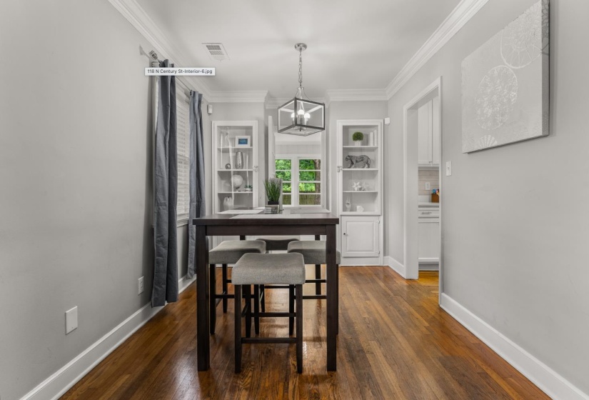 Dining space featuring crown molding, dark wood-style floors, and hanging lights