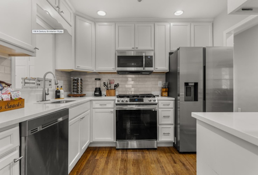 Kitchen with stainless steel appliances, white cabinetry, dark wood-type flooring, tasteful backsplash, and recessed lighting