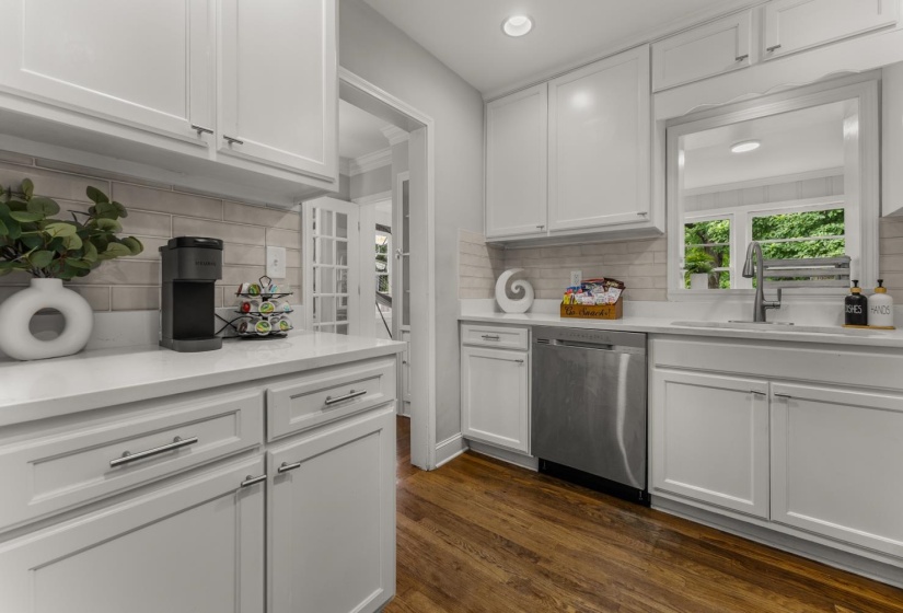 Kitchen with white cabinets, dark wood finished floors, dishwasher, light stone countertops, and recessed lighting