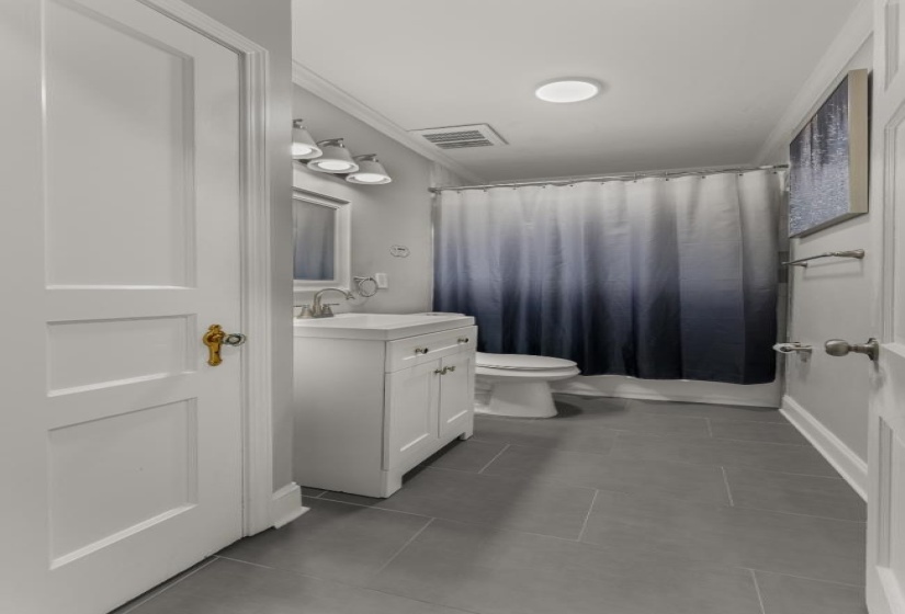 Bathroom featuring vanity, ornamental molding, light tile patterned flooring, and shower / bath combo