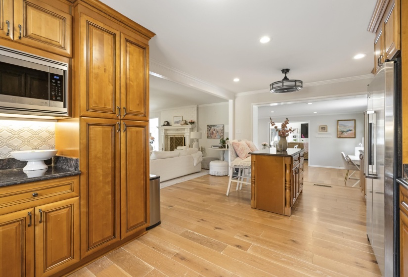 Kitchen with wood finish cabinets, dark stone countertops, open floor plan, ornamental molding, and stainless steel appliances