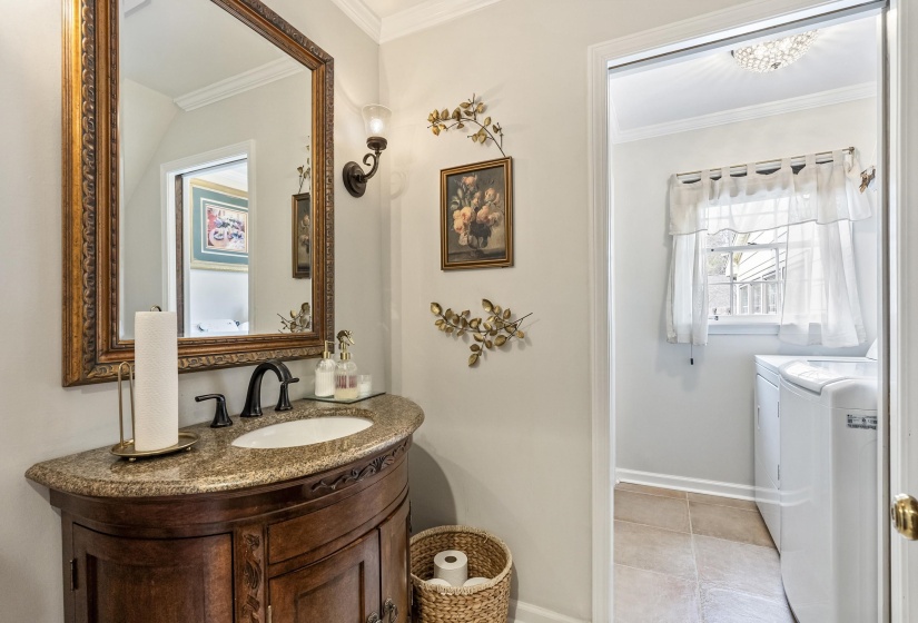 Half bath featuring vanity, crown molding, light tile patterned flooring, and washing machine and clothes dryer