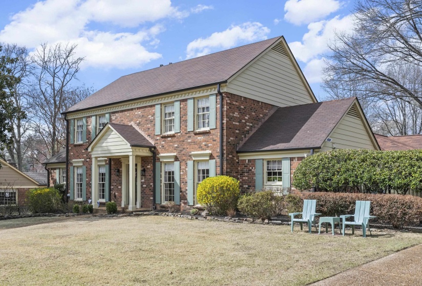 Colonial home with brick siding, a front lawn, and roof with shingles