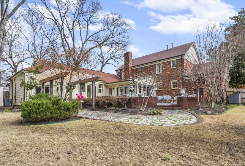 Rear view of house with a lawn, a chimney, and a patio