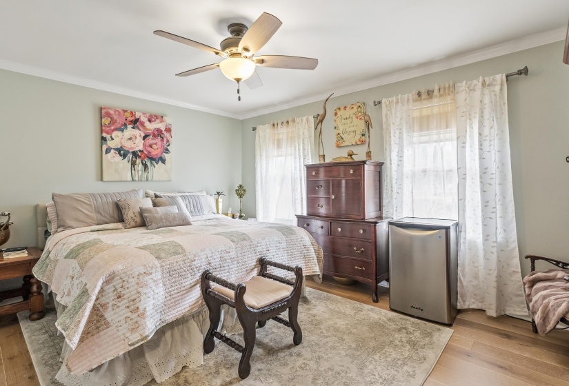 Bedroom with light wood finished floors, ornamental molding, a ceiling fan, and stainless steel fridge