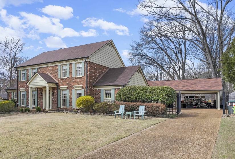 Colonial-style house featuring brick siding, a front lawn, concrete driveway, and a shingled roof
