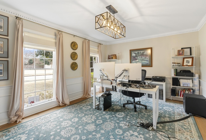 Office space with a wainscoted wall, a decorative wall, ornamental molding, and wood finished floors