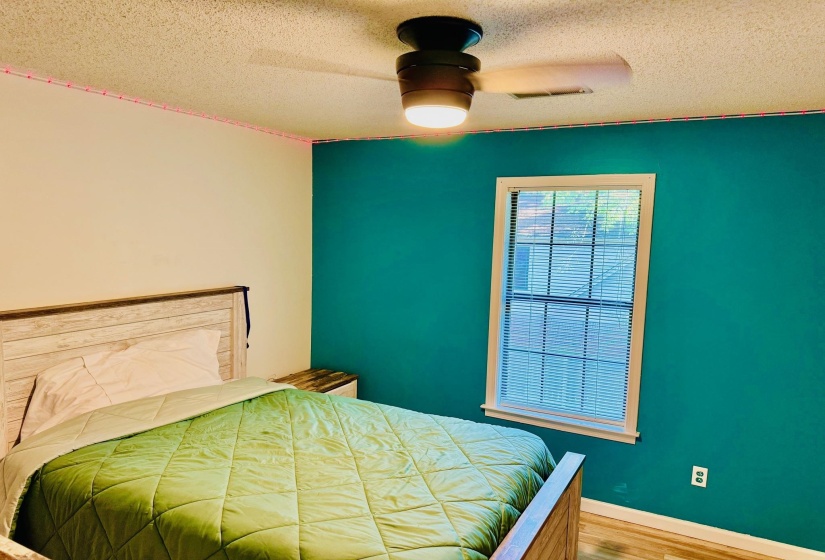 Bedroom with ceiling fan, a textured ceiling, and light wood-style flooring