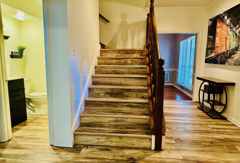 Staircase featuring wood finished floors and ornamental molding