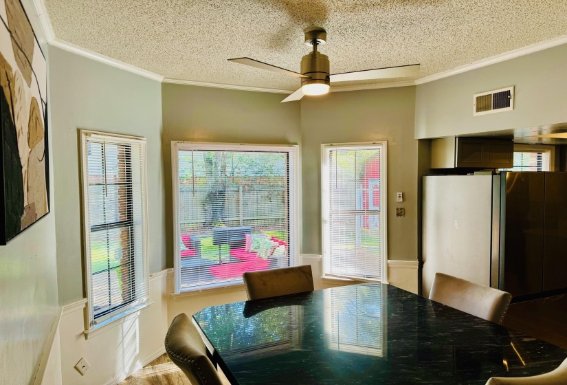 Dining area with a ceiling fan, ornamental molding, and a textured ceiling