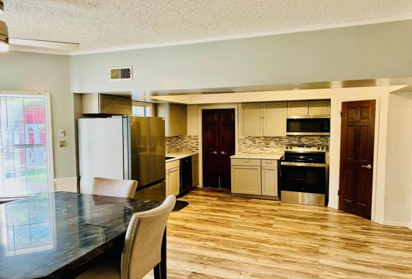 Kitchen featuring stainless steel appliances, backsplash, light wood finished floors, and crown molding