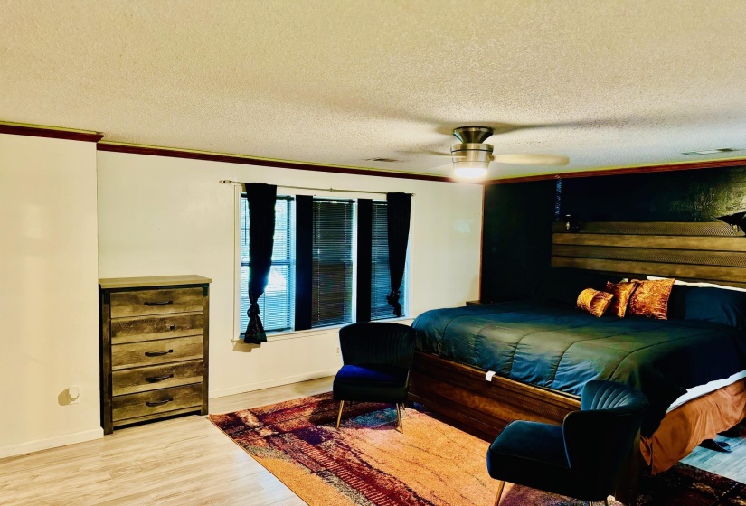 Bedroom featuring a textured ceiling, wood finished floors, a ceiling fan, and crown molding