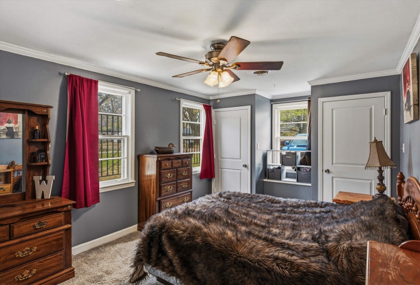 Bedroom with light colored carpet, ceiling fan, and ornamental molding