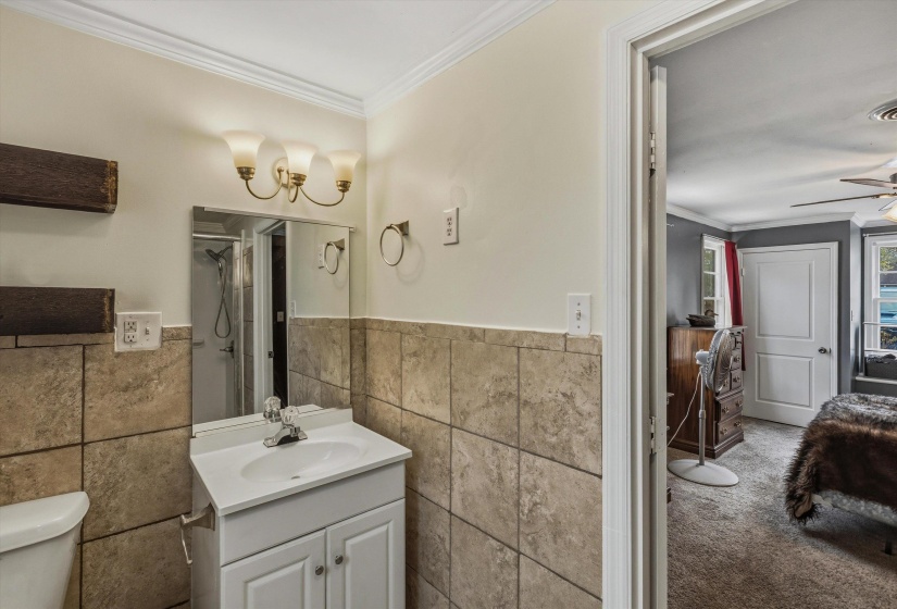 Bathroom featuring vanity, ornamental molding, a ceiling fan, tile walls, and a shower