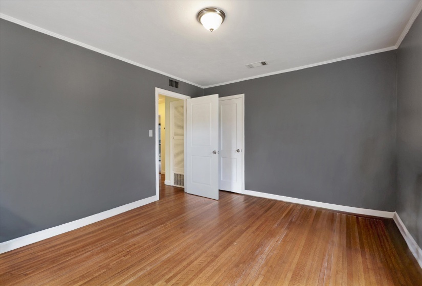 Unfurnished bedroom with light wood-style flooring, ornamental molding, and a closet