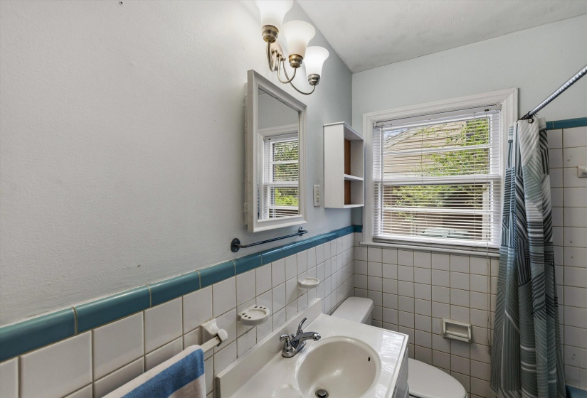 Bathroom with tile walls, a wainscoted wall, a shower with curtain, and vanity
