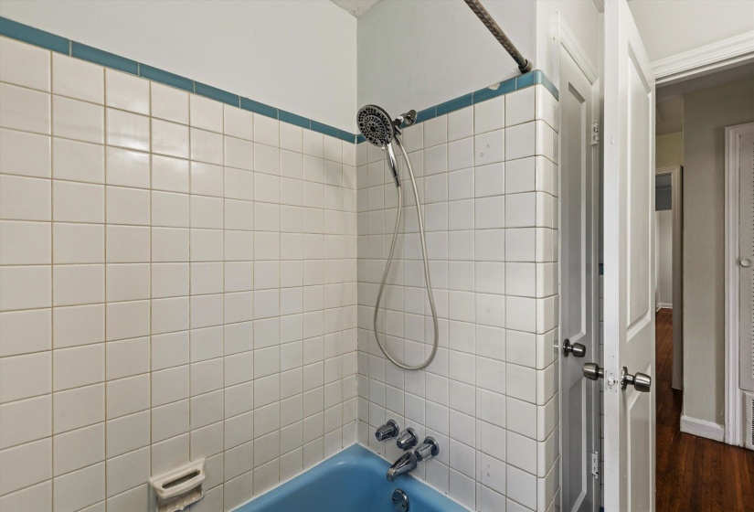Bathroom with bathing tub / shower combination and dark wood-style flooring
