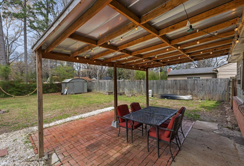 Fenced backyard with a patio, outdoor dining area, and a shed