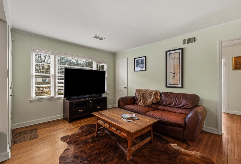 Living room with hardwood / wood-style flooring and crown molding