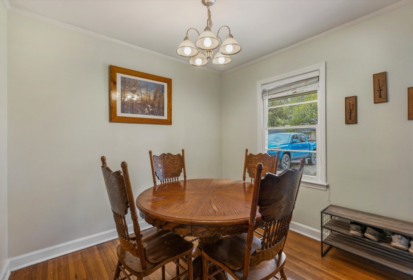 Dining area featuring hanging lights, dark wood-style flooring, and ornamental molding