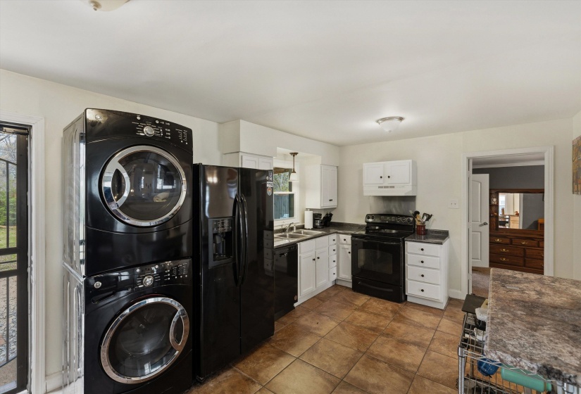 Kitchen with dark countertops, black appliances, white cabinetry, and dark tile patterned floors