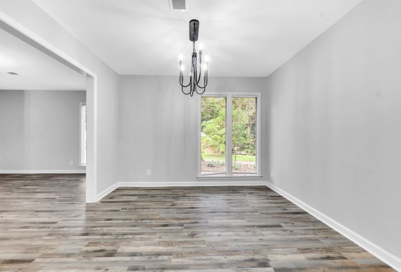 Unfurnished dining area with wood finished floors, a chandelier, and baseboards