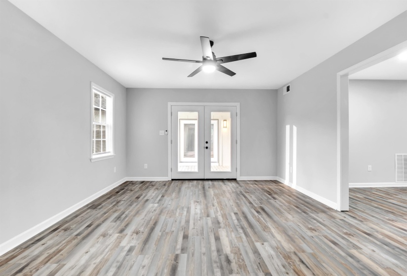 Empty room with a ceiling fan, wood finished floors, french doors, and baseboards