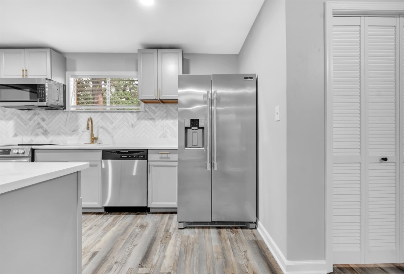 Kitchen with appliances with stainless steel finishes, decorative backsplash, light wood-type flooring, light countertops, and baseboards