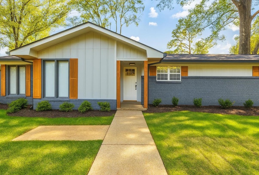 View of front of property featuring a front lawn, brick siding, and board and batten siding