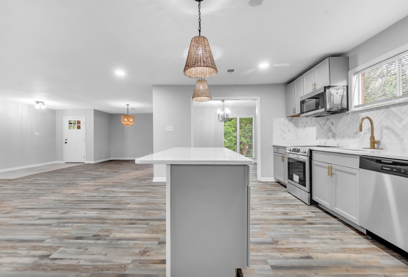 Kitchen with stainless steel appliances, a center island, light wood-type flooring, a sink, and light countertops