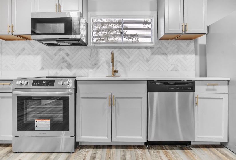 Kitchen with appliances with stainless steel finishes, light countertops, tasteful backsplash, and a sink