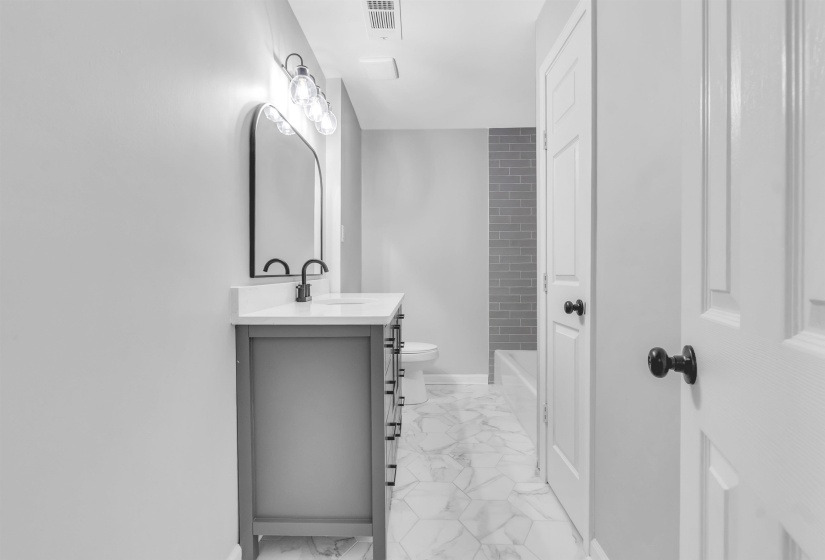Bathroom featuring marble look tile flooring, vanity, toilet, and baseboards